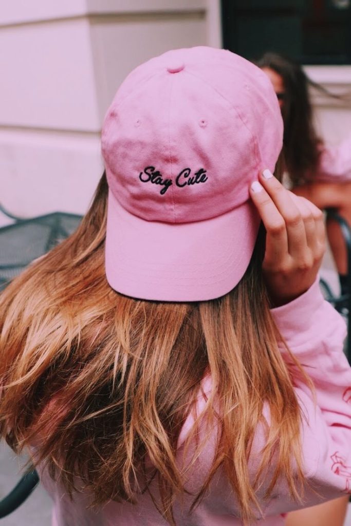 دخترک مو طلایی از نمای پشت با کلاه کپ صورتی برعکس